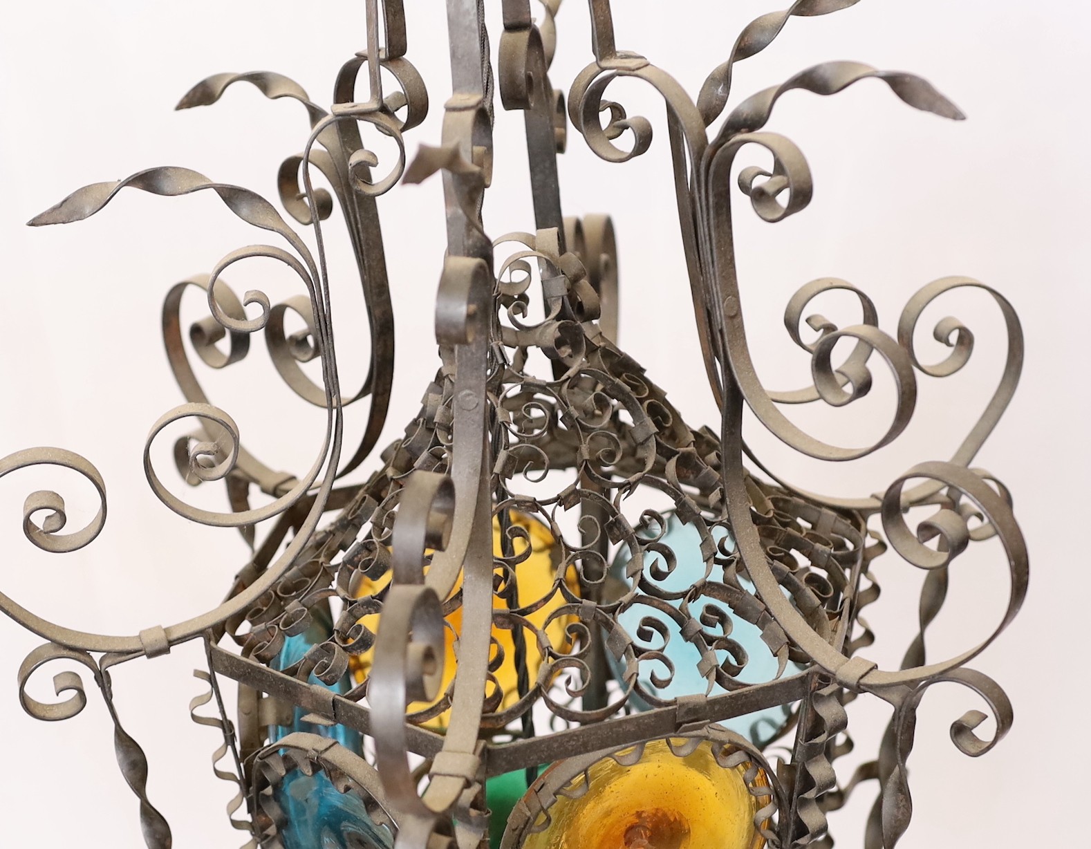 An early 20th century French wrought iron and coloured glass lantern of tapering hexagonal form, height 80cm. width 50cm